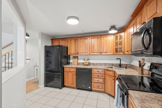 kitchen with black appliances, a sink, glass insert cabinets, and brown cabinetry