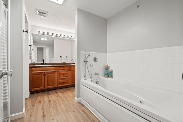 bathroom featuring a bath, wood finished floors, and vanity