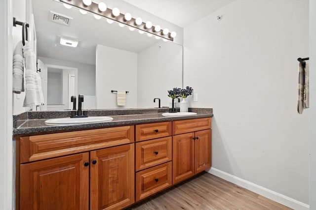 full bathroom featuring baseboards, wood finished floors, and double vanity
