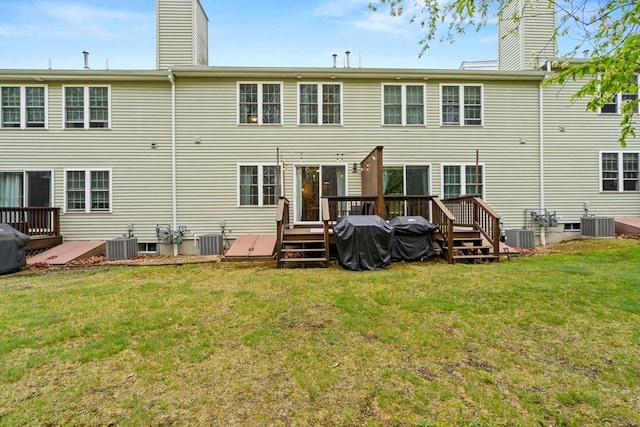 rear view of property featuring a chimney, a deck, central AC, and a yard