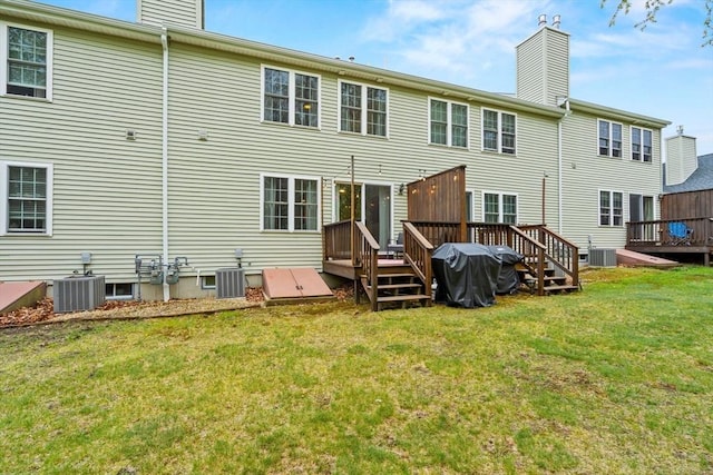 back of house featuring a deck, a chimney, a yard, and cooling unit