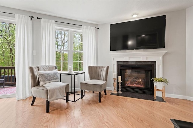 living area featuring wood finished floors, a fireplace with flush hearth, and baseboards