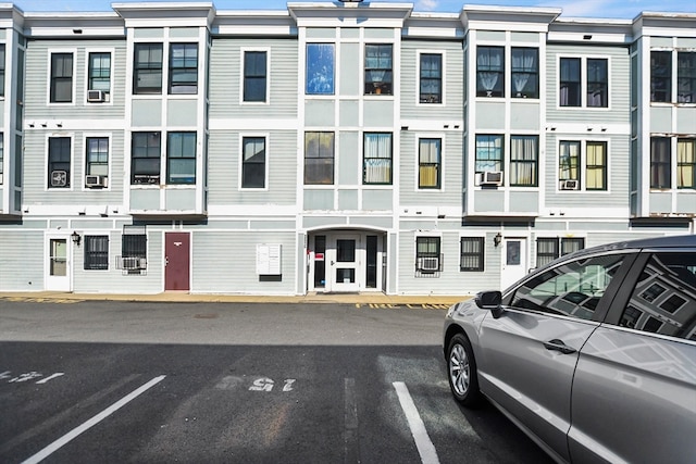 view of building exterior with uncovered parking and cooling unit