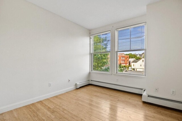 spare room with baseboard heating, baseboards, and wood finished floors