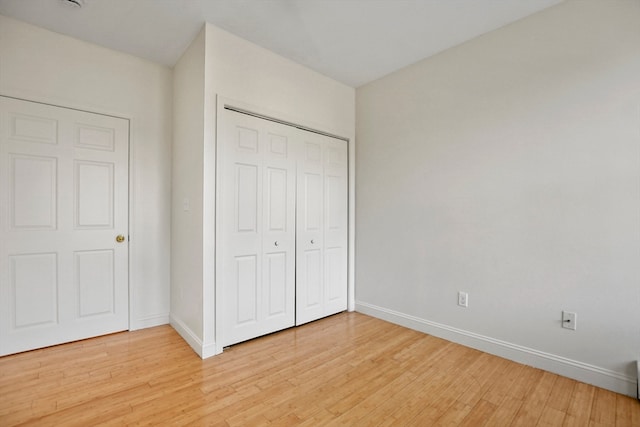 unfurnished bedroom with light hardwood / wood-style flooring and a closet