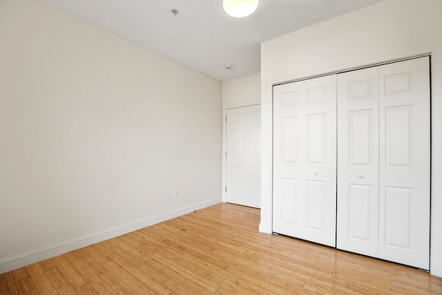 unfurnished bedroom with light hardwood / wood-style flooring and a closet