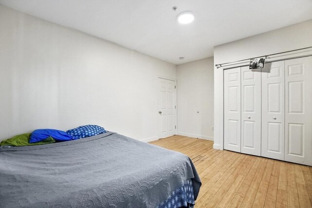 bedroom with a closet, light wood-style flooring, and baseboards