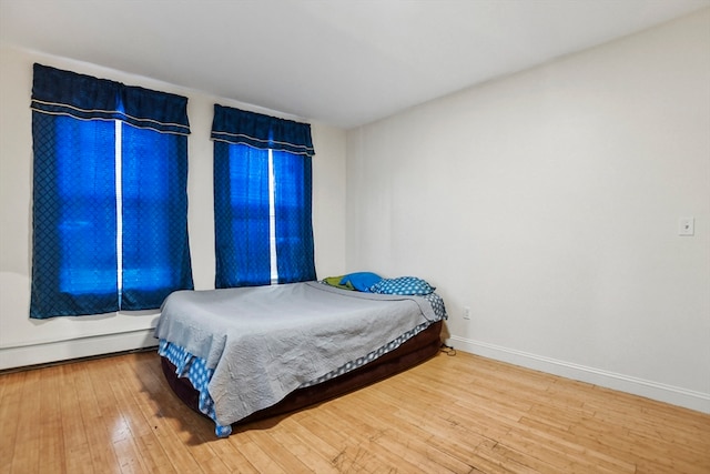 bedroom featuring hardwood / wood-style floors and a baseboard heating unit