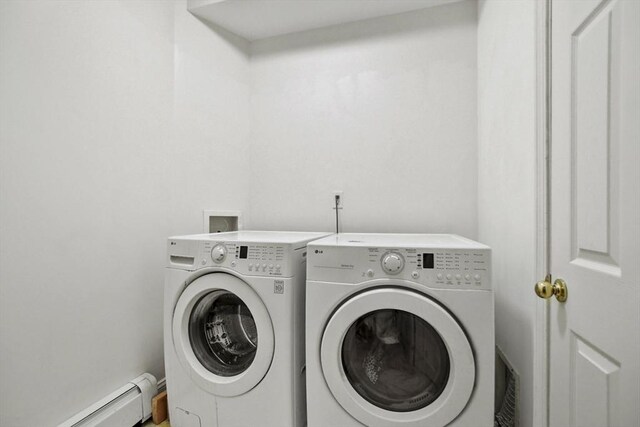 clothes washing area with washer and clothes dryer, baseboard heating, and laundry area