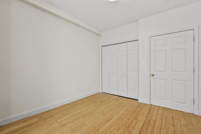 unfurnished bedroom featuring a closet, light wood finished floors, and baseboards