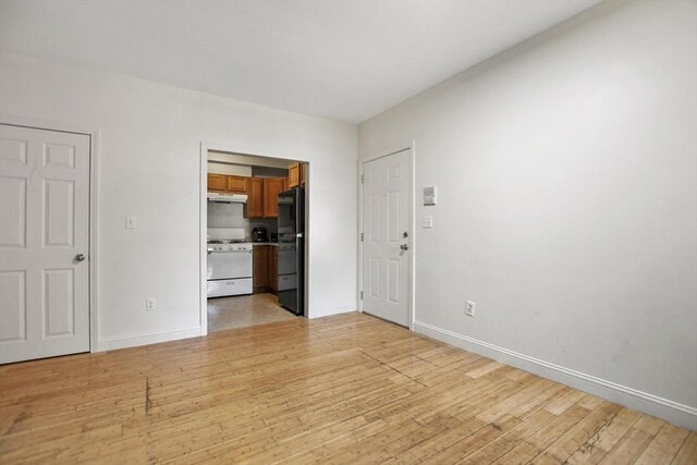 empty room with baseboards and light wood-style floors