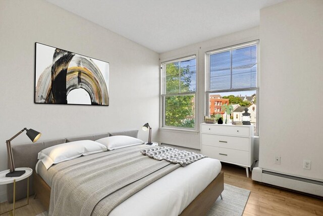 bedroom with baseboard heating and wood finished floors