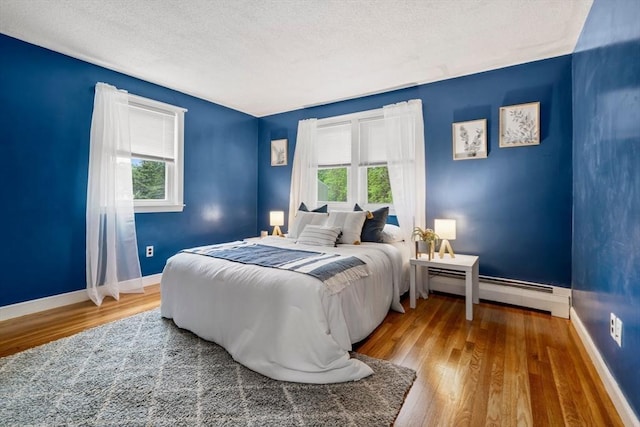21 Wilhelmina Ave, Burlington, MA 01803 - bedroom featuring multiple windows, wood finished floors, a baseboard radiator, baseboards, and a textured ceiling