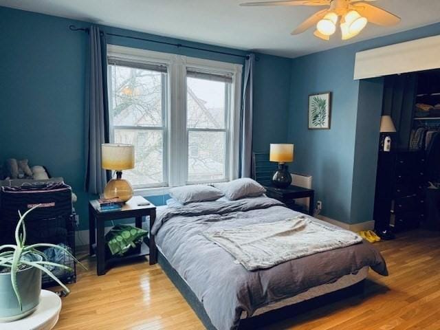 bedroom featuring a ceiling fan, wood finished floors, a closet, and baseboards