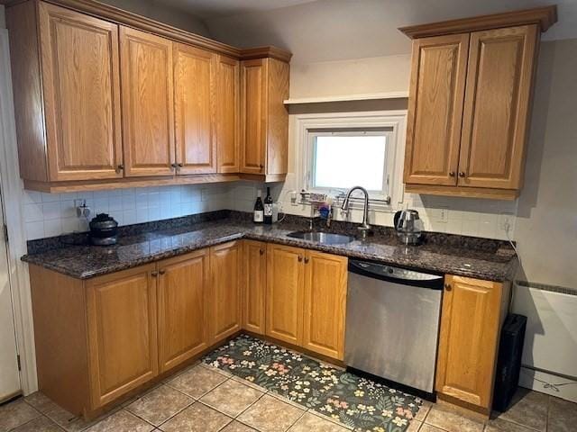 kitchen with tasteful backsplash, a sink, dark stone countertops, and stainless steel dishwasher