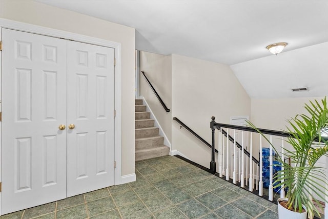 stairway featuring baseboards and lofted ceiling
