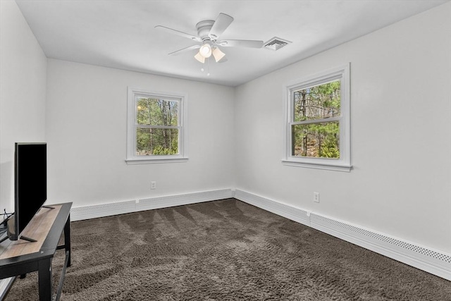unfurnished office featuring dark carpet, healthy amount of natural light, a ceiling fan, and baseboards