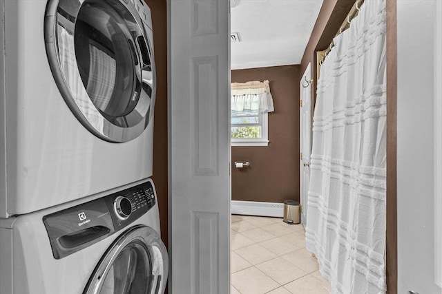 clothes washing area with stacked washer / dryer, light tile patterned floors, baseboards, and baseboard heating