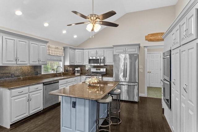 kitchen with appliances with stainless steel finishes, a sink, a breakfast bar area, dark wood-style floors, and recessed lighting