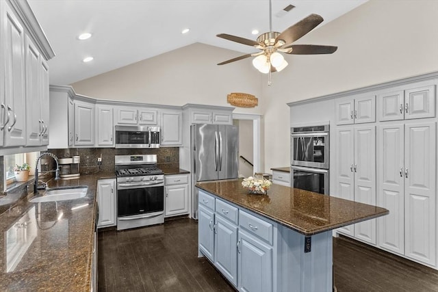 kitchen with stainless steel appliances, a sink, a ceiling fan, tasteful backsplash, and high vaulted ceiling