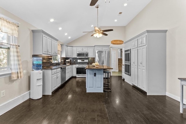 kitchen featuring stainless steel appliances, ceiling fan, dark countertops, gray cabinetry, and high vaulted ceiling