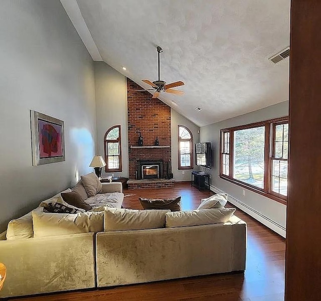 living room featuring high vaulted ceiling, ceiling fan, baseboard heating, a brick fireplace, and dark wood-type flooring