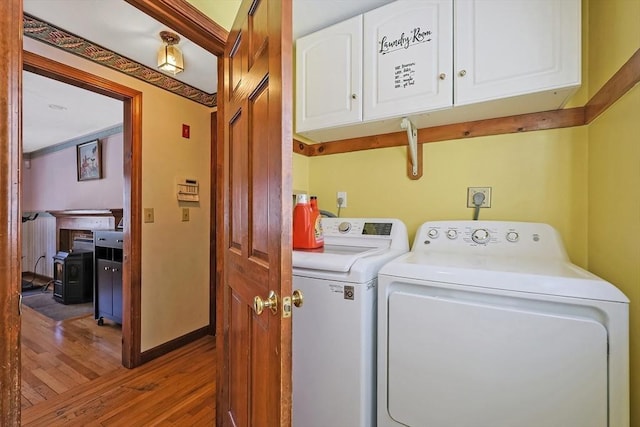 washroom featuring cabinet space, baseboards, wood finished floors, and washing machine and clothes dryer