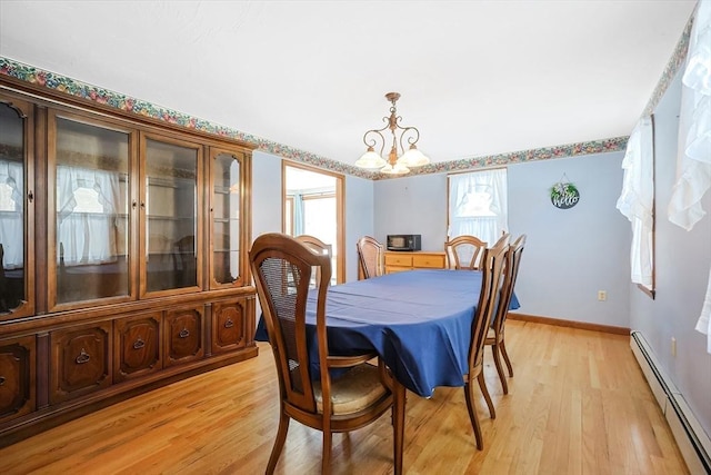 dining area featuring light wood-style floors, a baseboard radiator, a chandelier, and baseboards