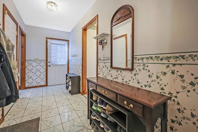 entrance foyer featuring marble finish floor, wainscoting, and wallpapered walls