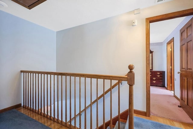 hallway featuring light wood-type flooring, baseboards, and an upstairs landing