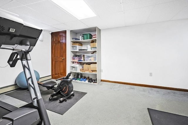 workout area featuring a baseboard heating unit, a paneled ceiling, and baseboards