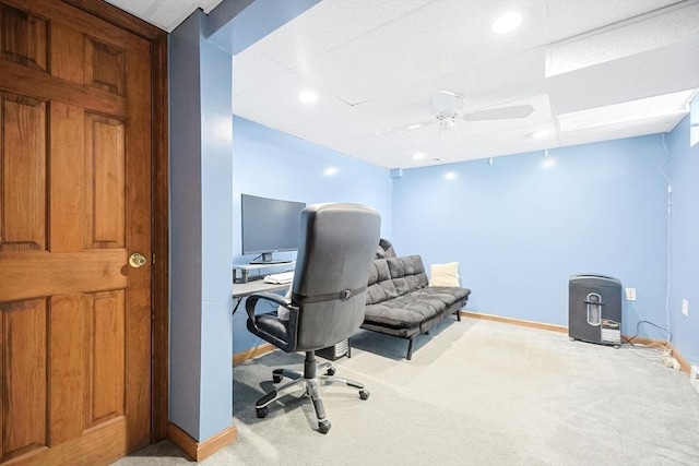 carpeted office space featuring ceiling fan and baseboards