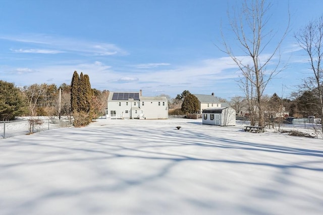 yard covered in snow with fence, a storage unit, and an outbuilding