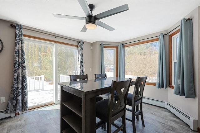 dining area featuring a ceiling fan, baseboard heating, and wood finished floors