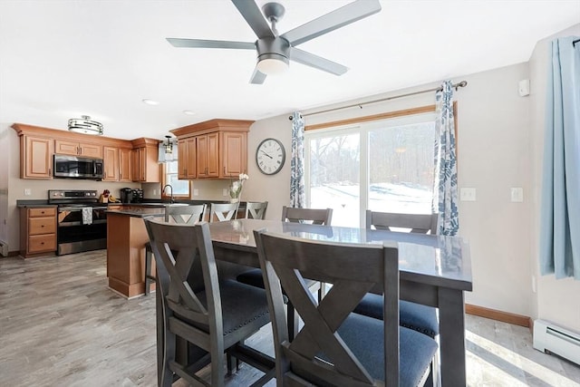 kitchen featuring stainless steel appliances, a peninsula, baseboards, baseboard heating, and dark countertops