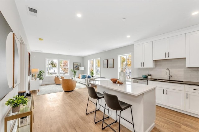1000 Washington St Unit 217, Dedham, MA 02026 - kitchen featuring a sink, open floor plan, a kitchen breakfast bar, a kitchen island, and light wood finished floors