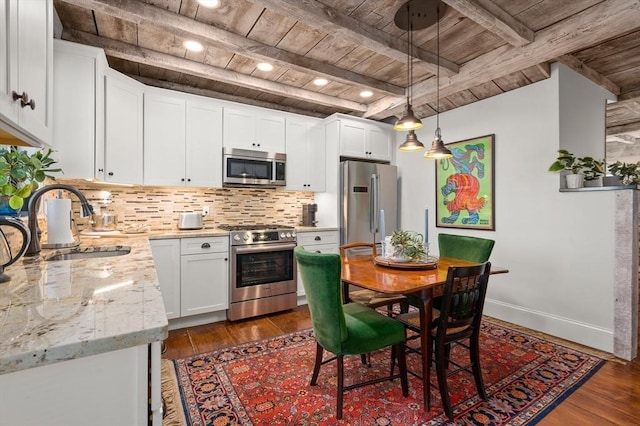 kitchen with pendant lighting, wood ceiling, white cabinets, appliances with stainless steel finishes, and sink