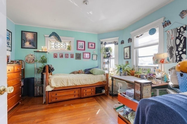 bedroom with crown molding and light hardwood / wood-style floors