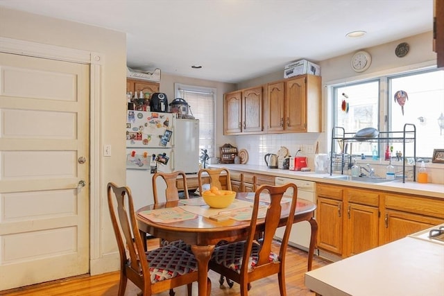 kitchen featuring tasteful backsplash, white dishwasher, sink, and light wood-type flooring