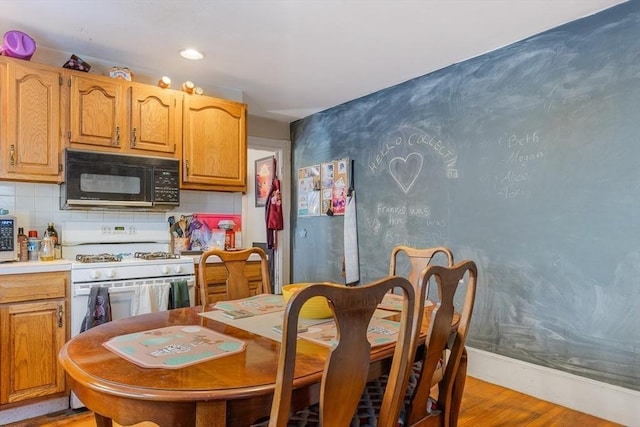 kitchen featuring white range with gas stovetop, backsplash, and light wood-type flooring