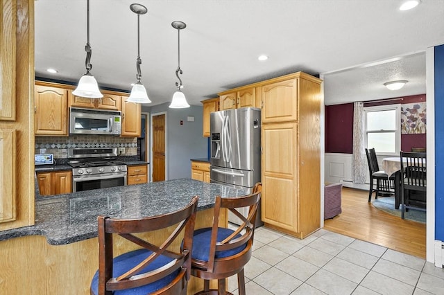 93 Lincoln Ave, Ashburnham, MA 01430 - kitchen featuring appliances with stainless steel finishes, dark countertops, a wainscoted wall, light tile patterned floors, and hanging light fixtures
