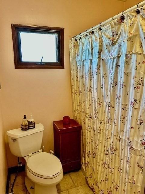 bathroom featuring tile patterned flooring, toilet, and walk in shower