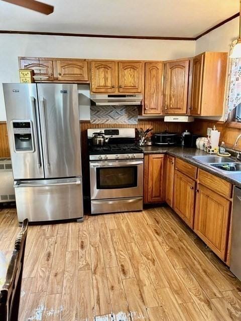 kitchen with ornamental molding, sink, stainless steel appliances, and light hardwood / wood-style floors