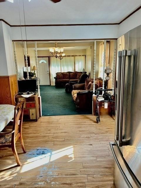 interior space featuring an inviting chandelier, ornamental molding, and light hardwood / wood-style flooring