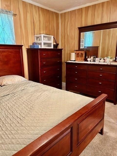 carpeted bedroom with crown molding and wooden walls