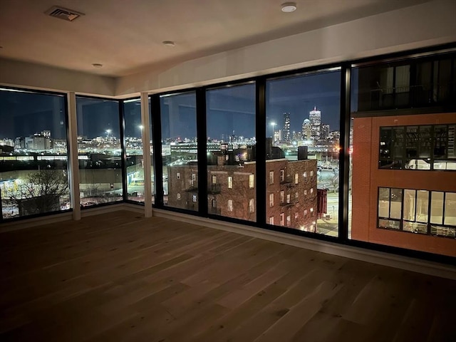 interior space with visible vents, a view of city lights, and wood finished floors