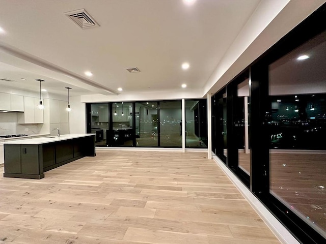 kitchen with light wood-style floors, a sink, visible vents, and white cabinetry