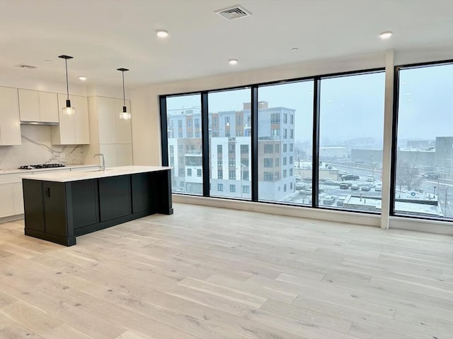 kitchen with visible vents, light countertops, light wood-style floors, gas stovetop, and white cabinetry