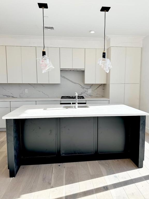 kitchen featuring white cabinets, modern cabinets, decorative backsplash, and a sink