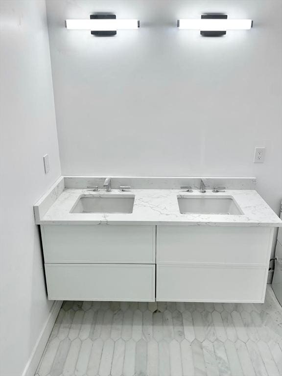 bathroom with double vanity, baseboards, and a sink